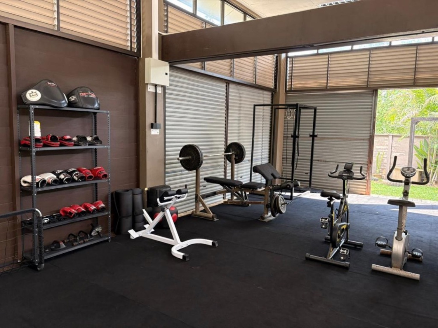 Bambu Getaway gym interior with benches, racks, boxing gloves on shelves and cardio bikes by open bay doors