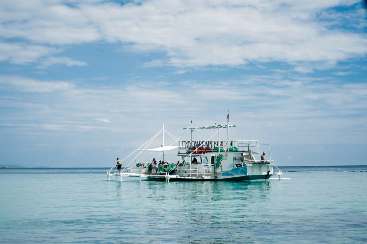 Illustrative island-hopping tour boat on turquoise water, evocative of Langkawi