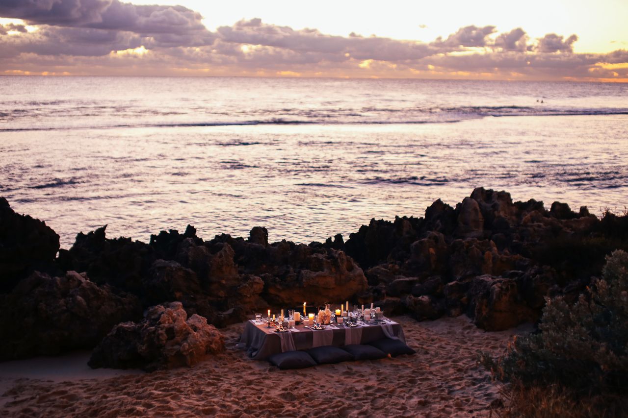 Candlelit private beach dinner at sunset, evocative of a Langkawi honeymoon