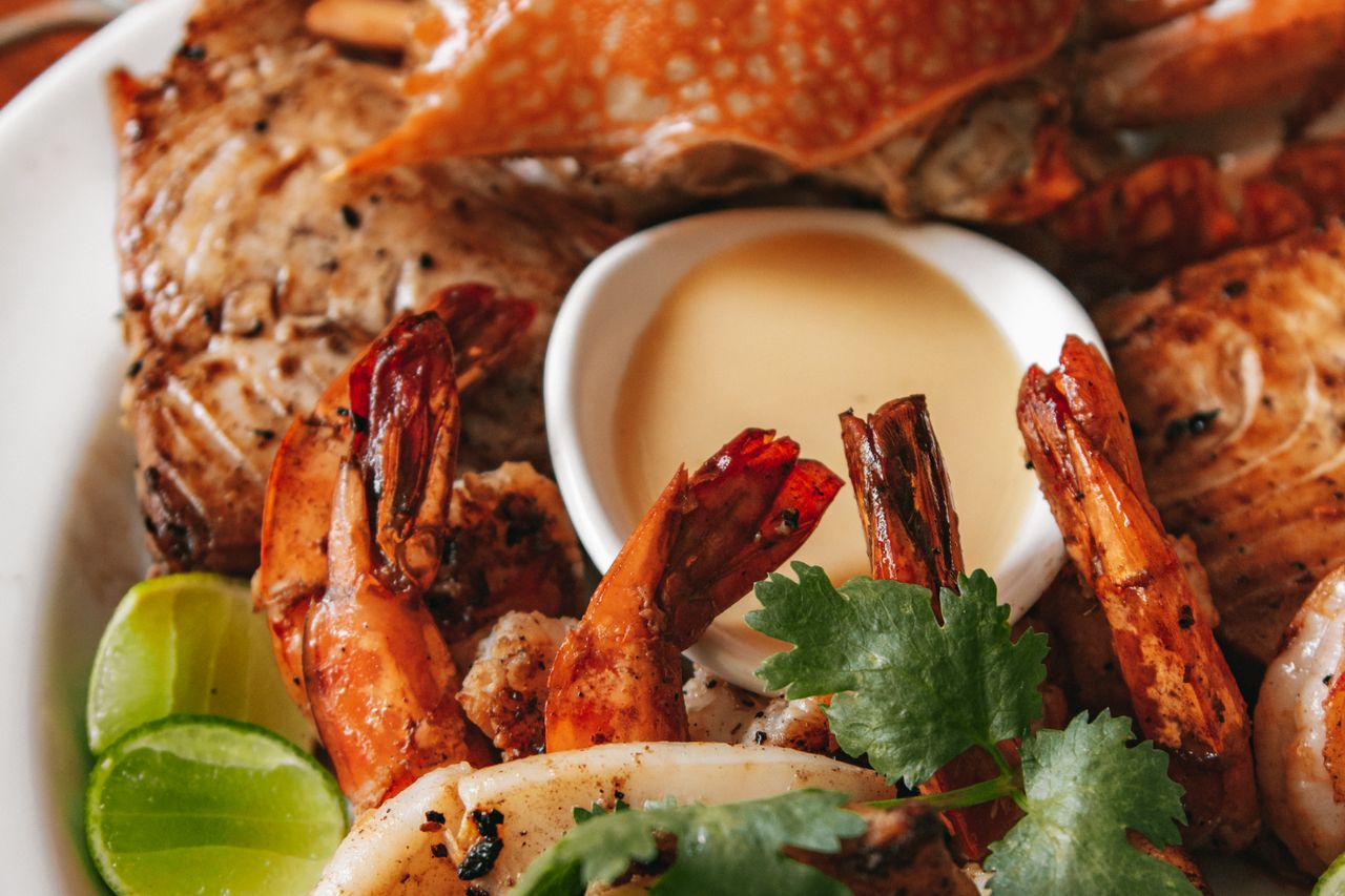 A grilled seafood platter with prawns, crab, fish and squid, lime and coriander