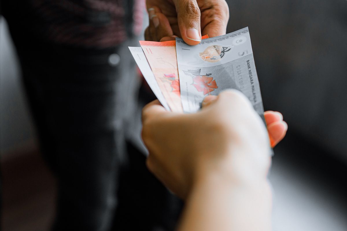 Hands exchanging Malaysian ringgit banknotes at a stall, Malaysia