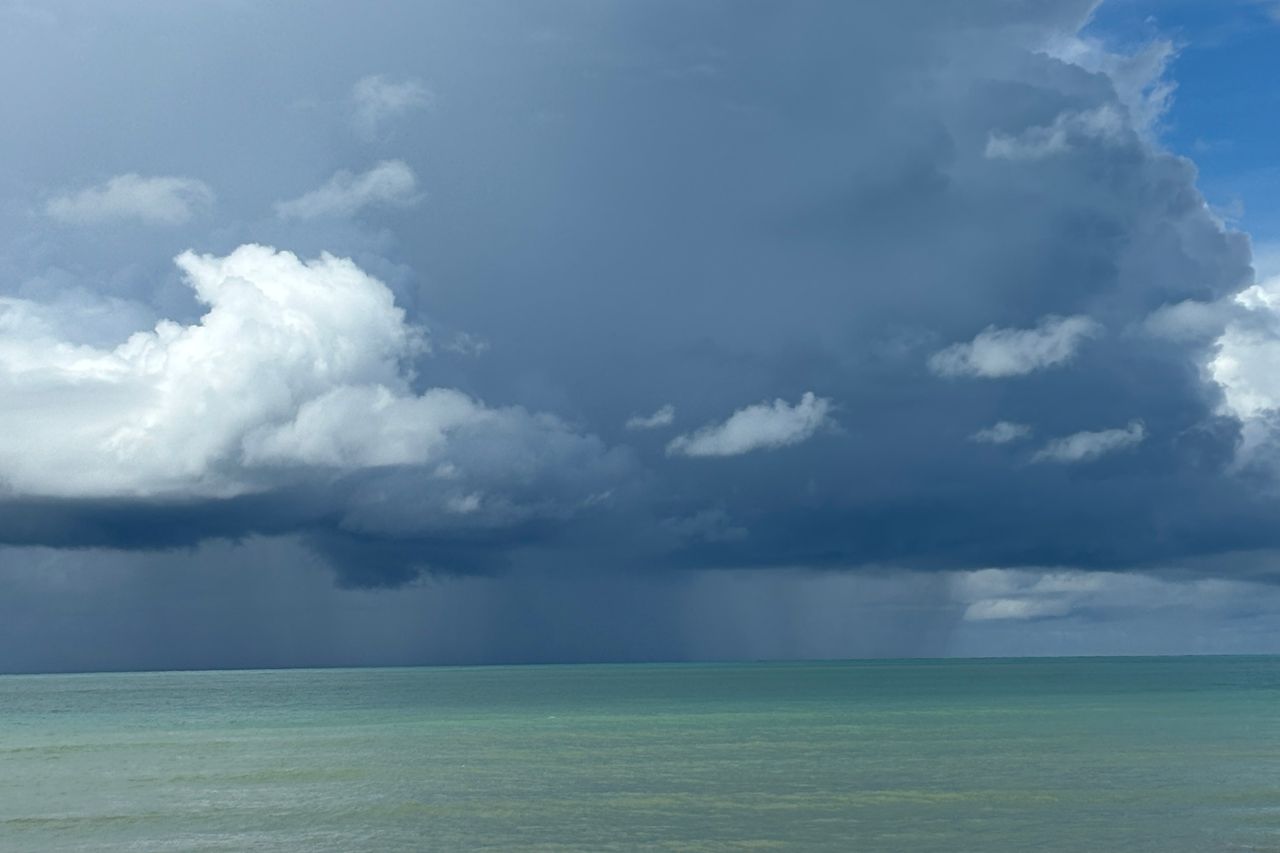 A rain squall and monsoon clouds over a turquoise tropical sea