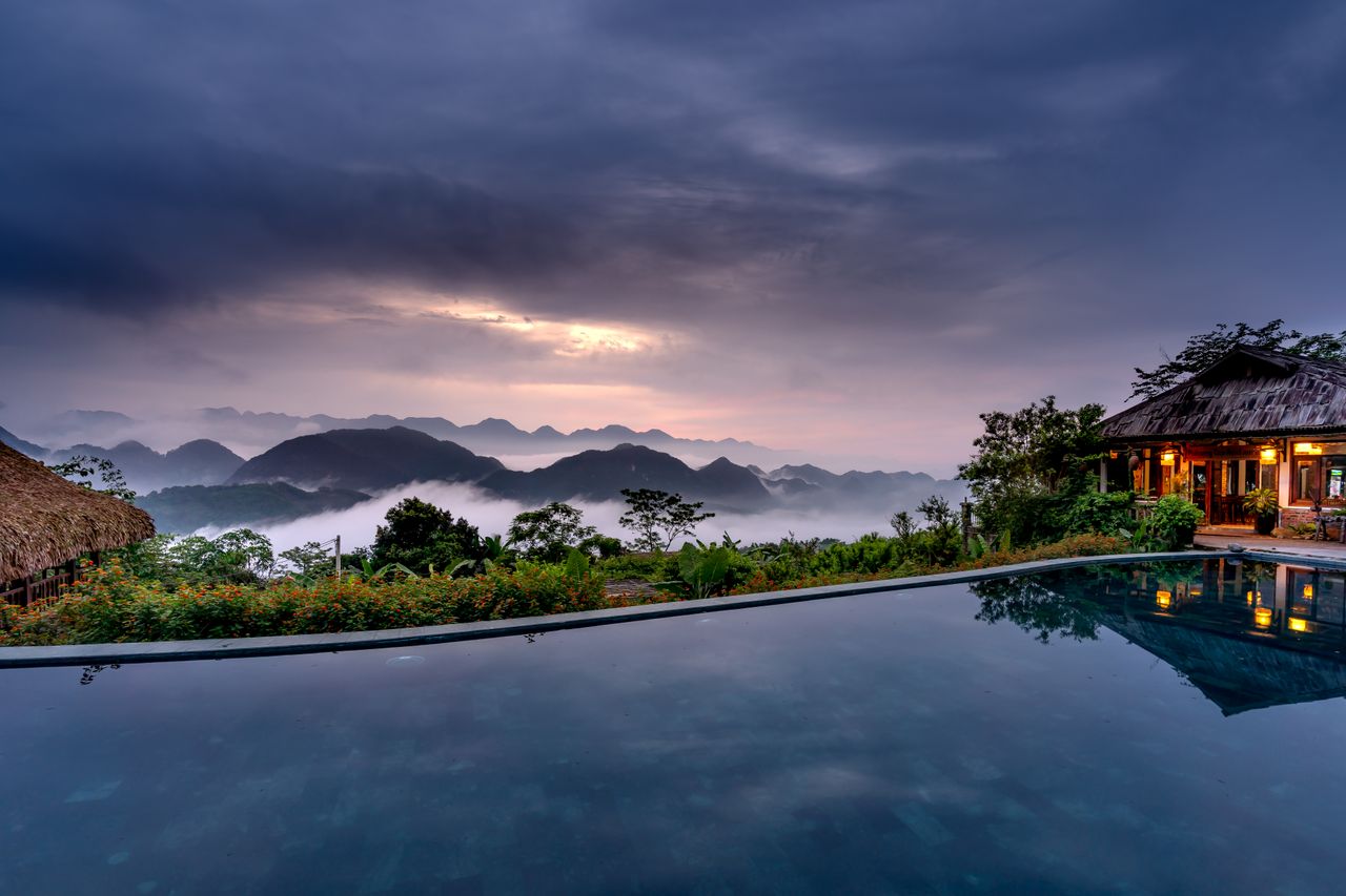 A tropical infinity pool overlooking misty mountains under moody monsoon clouds